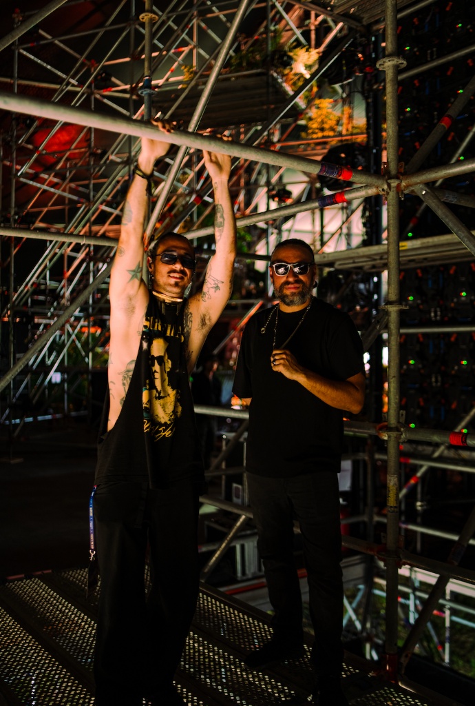 The duo behind The Dark Wave backstage among stage scaffolding at night