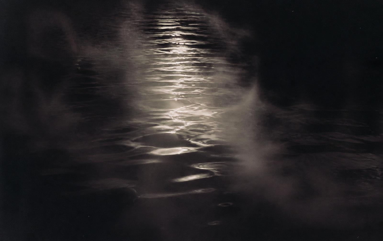 Moonlight rippling across dark water in drifting mist
